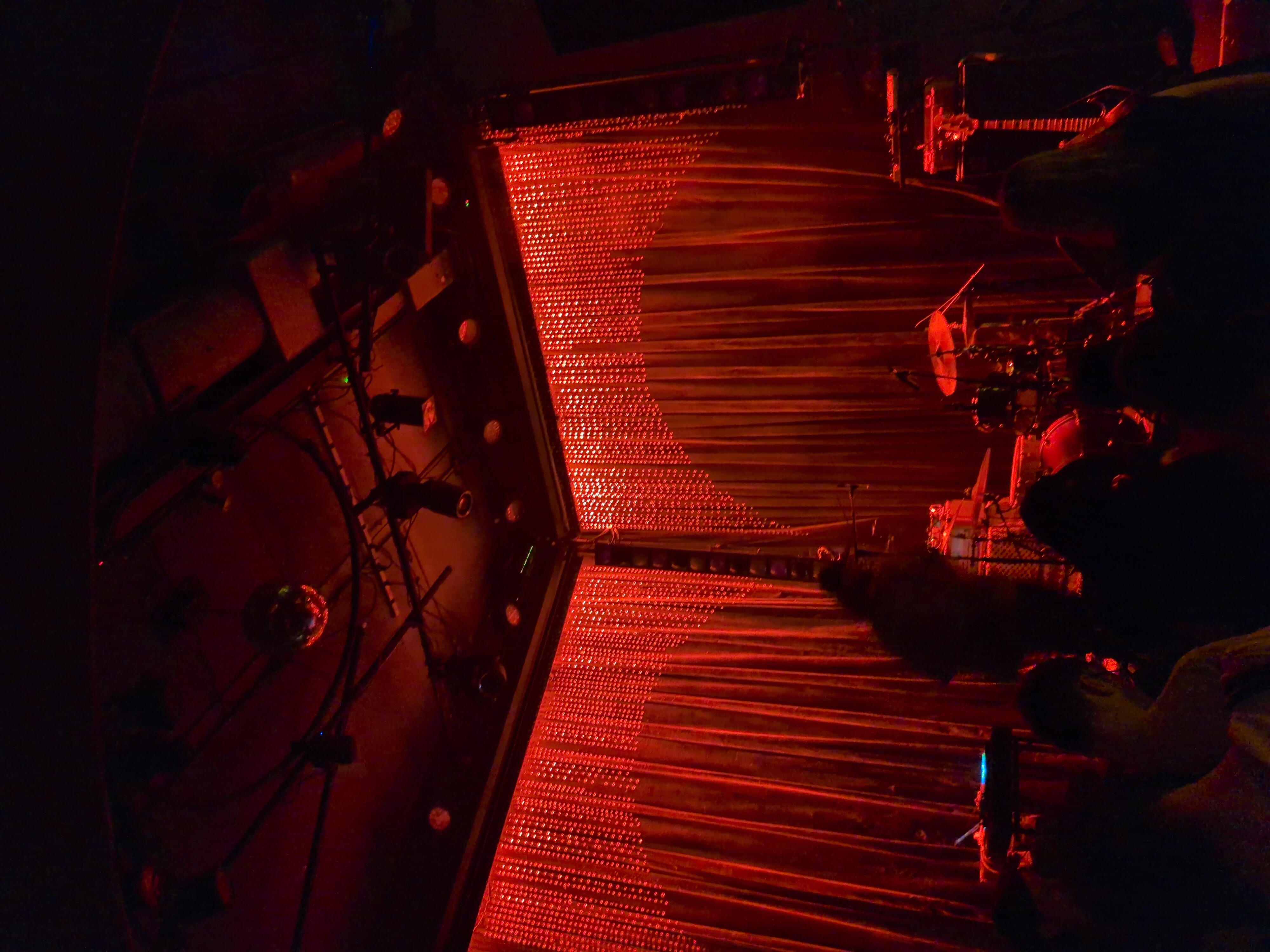 Stage at Johnny Brenda’s the stage is backed by beads flowing down from the ceiling and it is lit with red light
